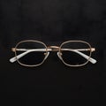 Gold rimmed glasses create striking contrast against black background