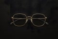 Gold rimmed glasses create striking contrast against black background