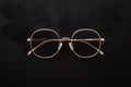 Gold rimmed glasses create striking contrast against black background