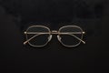 Gold rimmed glasses create striking contrast against black background