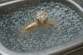 A gold ring with a brilliant diamond is immersed in a cleansing solution during a jewelry cleaning process Royalty Free Stock Photo