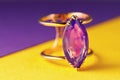 Gold ring with a large amethyst on a colored background