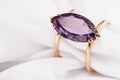 Gold ring with a large amethyst on silk fabric with copy space