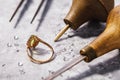 Gold ring with precious stones on the table, surrounded by jewelry repair tools