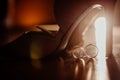 Gold rings stand next to the floor under the shoes of the bride