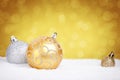 Gold and silver Christmas baubles on snow, gold background Royalty Free Stock Photo