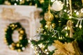 Gold and silver Christmas toys, balls and garlands on a spruce branch on christmas tree against the background of a fireplace with Royalty Free Stock Photo