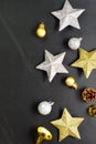 Gold-silver colored stars, gift box and decorative balls on black background with copy space.
