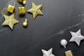 Gold-silver colored stars, gift box and decorative balls on black background with copy space.