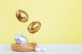 Gold and silver Easter eggs levitation to the nest on a yellow background. Easter concept. Copy space Royalty Free Stock Photo