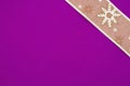 Gold snowflake ribbon on bright purple textured felt material background