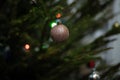 Gold sparkly Christmas bauble on branch of a real Christmas tree. Royalty Free Stock Photo