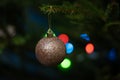 Gold sparkly Christmas bauble on branch of a real Christmas tree. Royalty Free Stock Photo