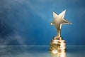 Gold star trophy in smoke, blue background