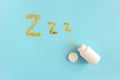 Gold stars confetti fly out white bottle in form of dream symbols Z Z Z on blue background. Concept Insomnia, sleep problems and