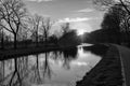 Gold sunset over river with sun rays, tree silhouettes and reflection on water in black and white