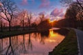 Gold sunset over river with sun rays, tree silhouettes and reflection on water Royalty Free Stock Photo