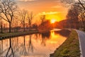 Gold sunset over river with sun rays, tree silhouettes and reflection on water