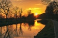 Gold sunset over river with sun rays, tree silhouettes and reflection on water