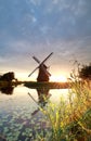 Gold sunshine behind Dutch windmill by river