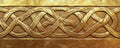 A gold textured surface with intricate, Celtic knotwork patterns engraved into the metal, adding a Royalty Free Stock Photo