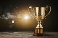 Gold trophy over wooden table and dark background with abstract shiny lights, symbolizing victory Royalty Free Stock Photo