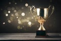 Gold trophy over wooden table and dark background with abstract shiny lights, symbolizing victory Royalty Free Stock Photo