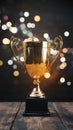 Gold trophy over wooden table and dark background with abstract shiny lights, symbolizing victory Royalty Free Stock Photo