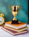 gold trophy sits on top of books next to an alarm clock