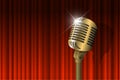 Gold vintage microphone illuminated and red curtain background. Retro music concept. Mic on empty theatre stage. Stand Royalty Free Stock Photo