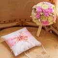 Gold wedding rings and a bouquet of the bride. Pink and white roses. Satin decorative cushion for the rings Royalty Free Stock Photo