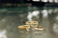 Gold wedding rings, an engagement ring and a foil ring on a blurred background with water drops. Royalty Free Stock Photo