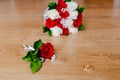 Gold wedding rings, groom`s boutonniere and bride`s bouquet of red and white roses on a wooden background. wedding Royalty Free Stock Photo