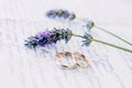 Gold wedding rings on a leaf covered with lavender sprigs.