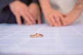 Gold wedding rings lie on the table behind them blurred the hands of the newlyweds. Bride hand with ring a bouquet Royalty Free Stock Photo