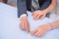 Gold wedding rings lie on the table behind them blurred the hands of the newlyweds. Bride hand with ring a bouquet Royalty Free Stock Photo