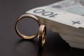 Gold wedding rings surrounded by a stack of Polish banknotes Royalty Free Stock Photo