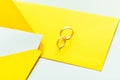 Gold wedding rings on the yellow letter invitation on the white background Royalty Free Stock Photo