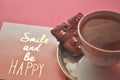 Gold and white porcelain tea cup and saucer with artisan chocolate on bright fuchsia pink background with copy space