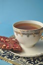 Gold and white porcelain tea cup and saucer with artisan chocolate and open book on blue background with copy space