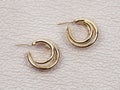 Gold women`s earrings on beige leather background