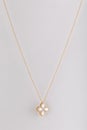 Gold womens chain with a pendant in the shape of a flower with a white stone in the edging isolated on a white background.