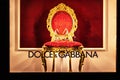 Gold womens shoes on a red velvet chair, in a classic style. The inscription in English on the window DOLCE GABANNA