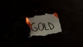 Gold word written on white paper burns. Fire with smoke and ashes on black background Royalty Free Stock Photo