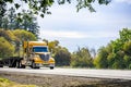 Gold yellow bonnet big rig semi truck transporting empty step down semi trailer running by highway road to warehouse for the next Royalty Free Stock Photo