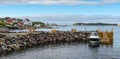 Golden adirondack chairs on a rock jetty. Houses on the sea along a village shoreline. Royalty Free Stock Photo