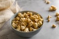 Golden airy popcorn in a gray plate on a concrete table on a piece of light burlap, fried crispy corn for watching a movie or