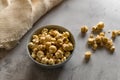 Golden airy popcorn in a gray plate on a concrete table on a piece of light burlap, fried crispy corn for watching a movie or