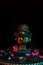 Golden angel sculpture adorned with flowers on a glass with warm and cold lights on a dark background