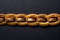 Golden antique jewelry chain on an isolated black background. Part of an old retro bracelet with links. Gold vintage Royalty Free Stock Photo